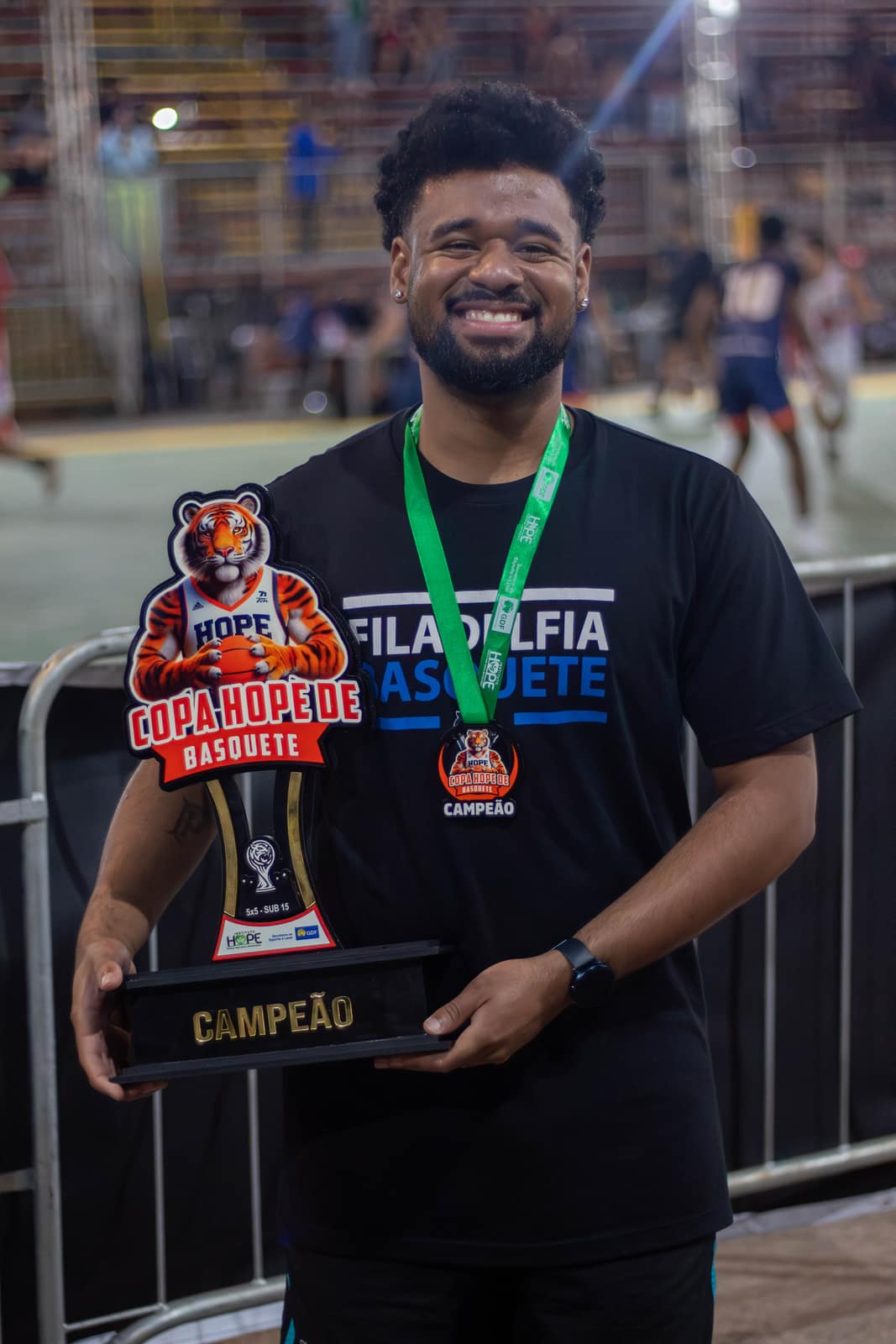 Integrante da comissão técnica com o troféu de campeão da Copa Hope de Basquete